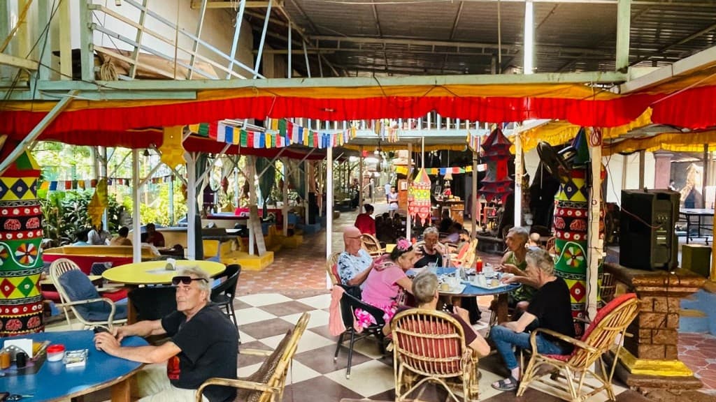 Guests seated under colourful fabric and prayer flags at German Bakery, Anjuna