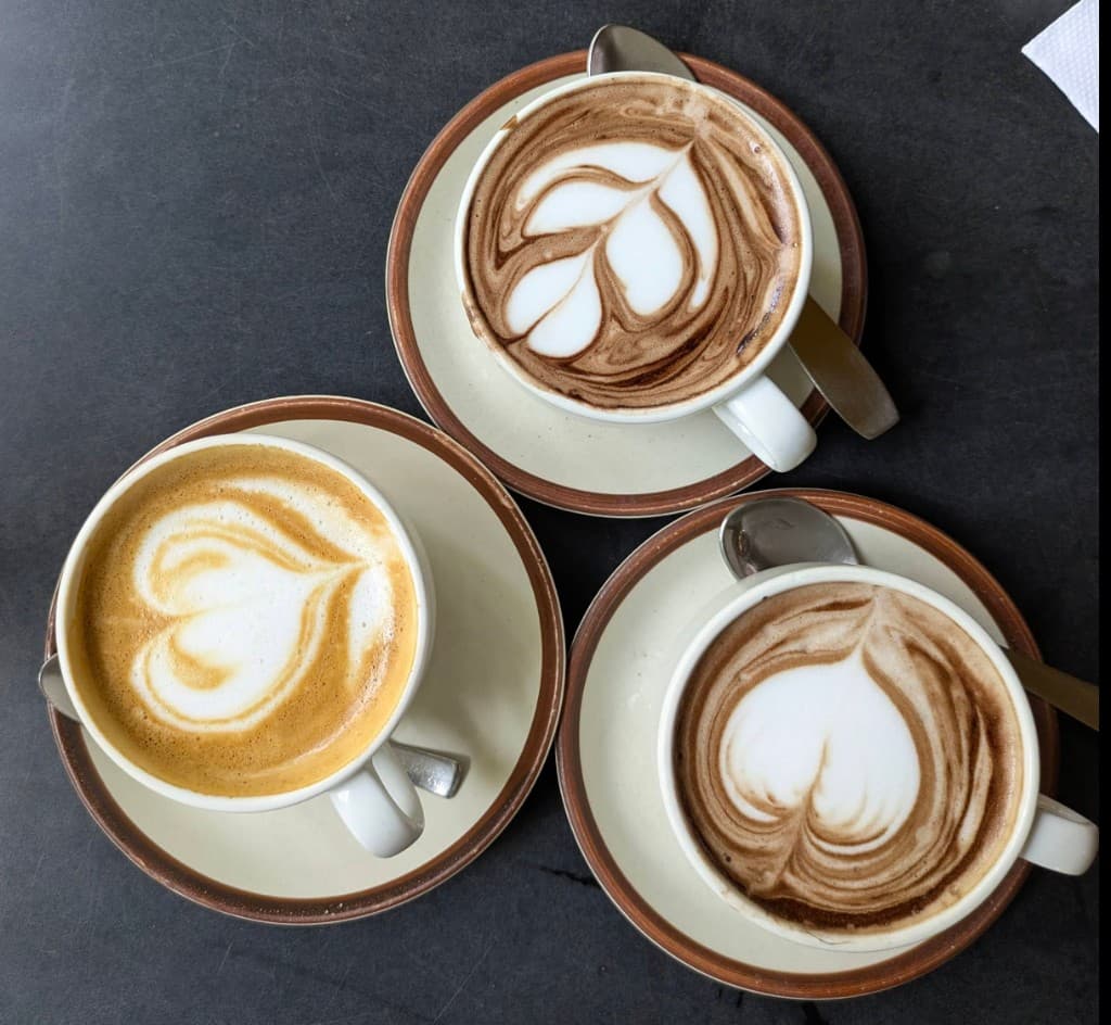 Three cups of coffee with latte art at German Bakery, Anjuna