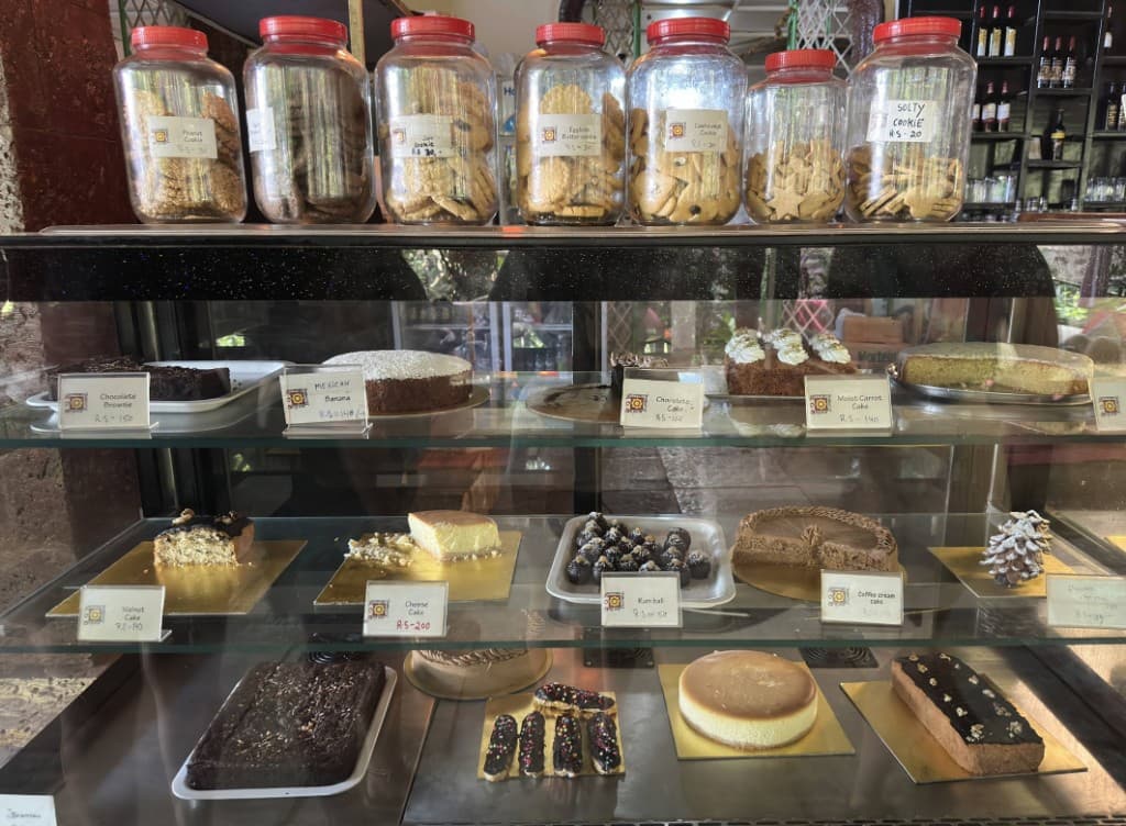 Bakery display case with cakes, cookies in jars, and desserts at German Bakery, Anjuna